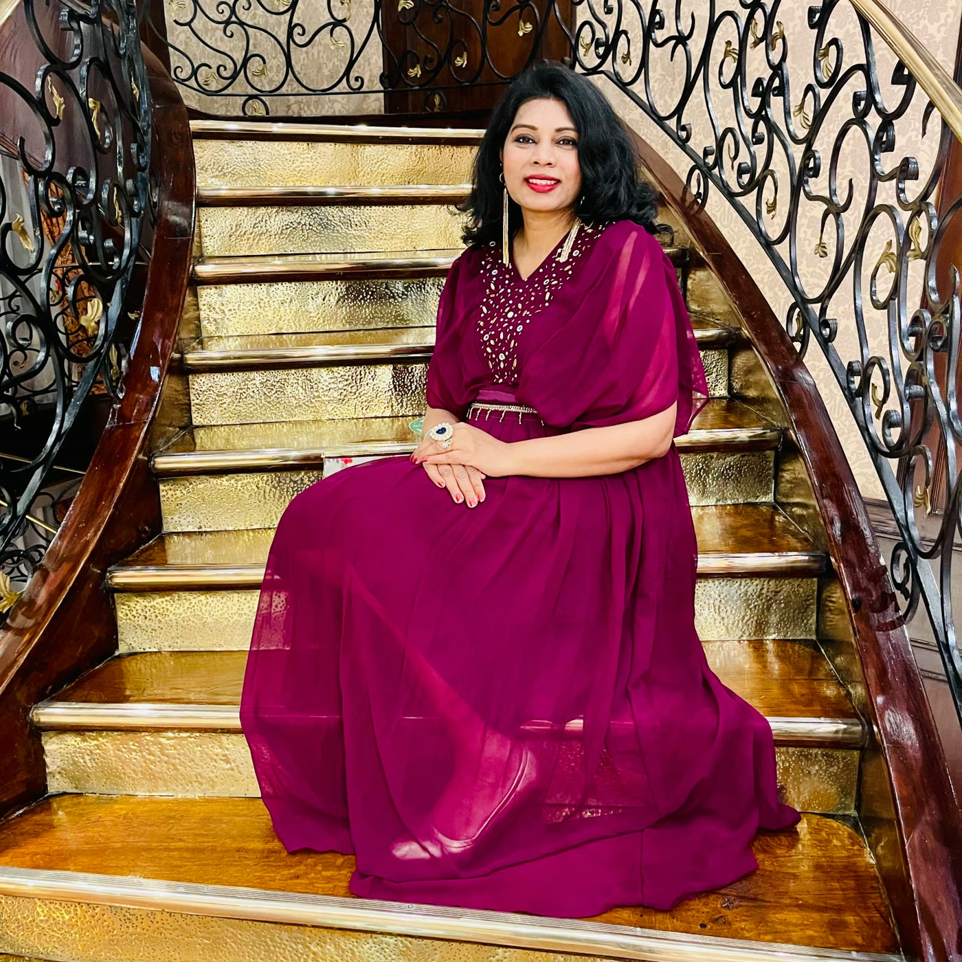 Bindu Bodanapu, Divine Feminine Leadership Coach, in a magenta gown on a grand staircase